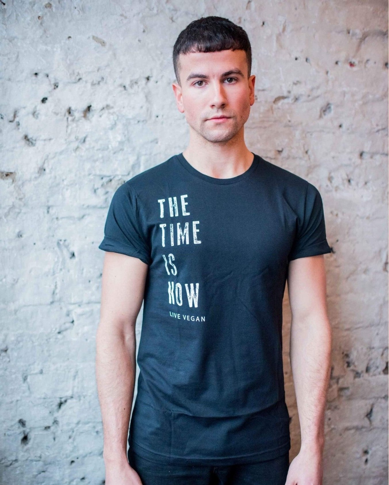 A short haired male model standing in front of wall wearing Viva La Vegan&