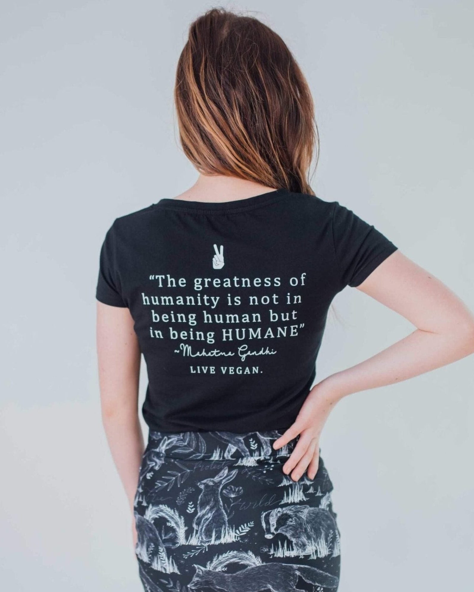 Female modelling the back of a black humane being vegan tshirt on a white background on behalf the Eco ethical vegan brand Viva La Vegan.