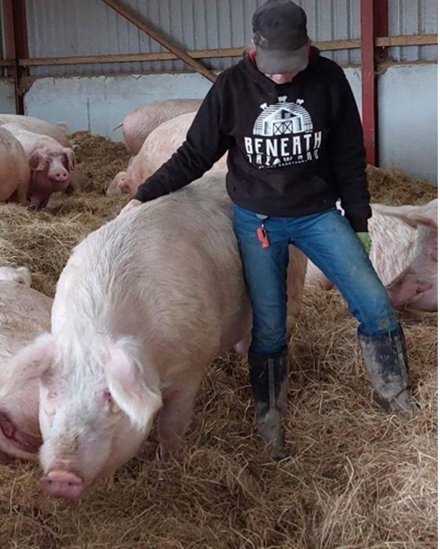 Sasha standing up stroking a pig wearing a black hoodie with white print &amp; hot pink trims. By Viva La Vegan. Fund raising for Beneath The Wood Sanctuary