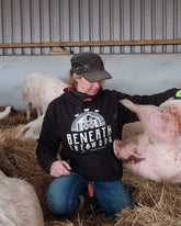Sasha sat stroking a pig wearing a black hoodie with white print & hot pink trims. By Viva La Vegan. Fund raising for Beneath The Wood Sanctuary