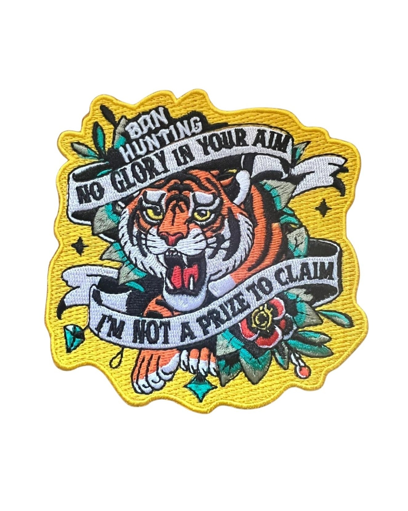 Embroidered patch featuring a roaring tiger surrounded by floral motifs and bold banners. Text reads: “Born Hunting / No Glory In Your Aim / I&