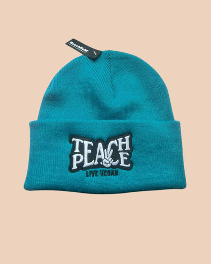 Flatlay photo of a cuffed beanie in petrol colour with a black and white embroidery &
