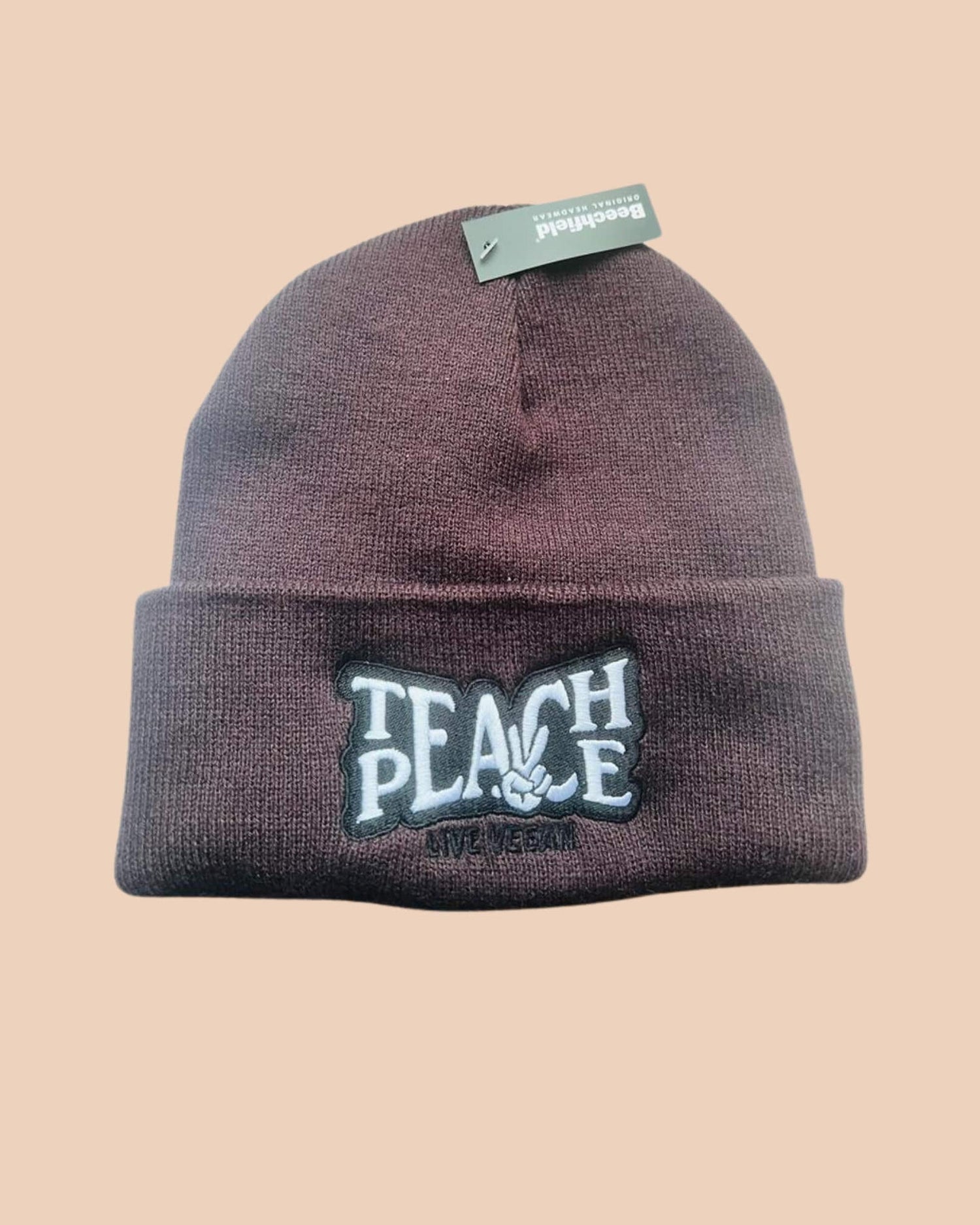 Flatlay photo of a cuffed beanie in plum colour with a black and white embroidery &