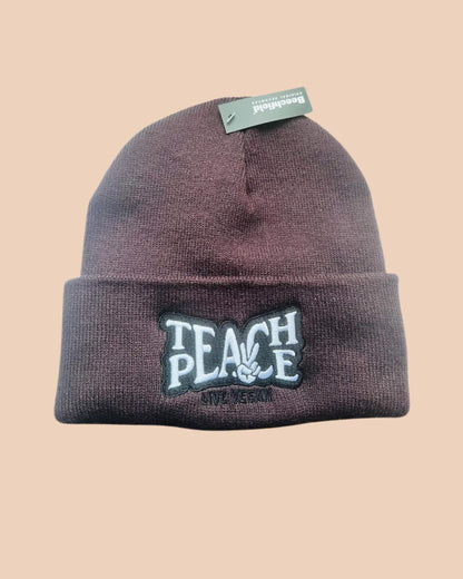 Flatlay photo of a cuffed beanie in plum colour with a black and white embroidery &
