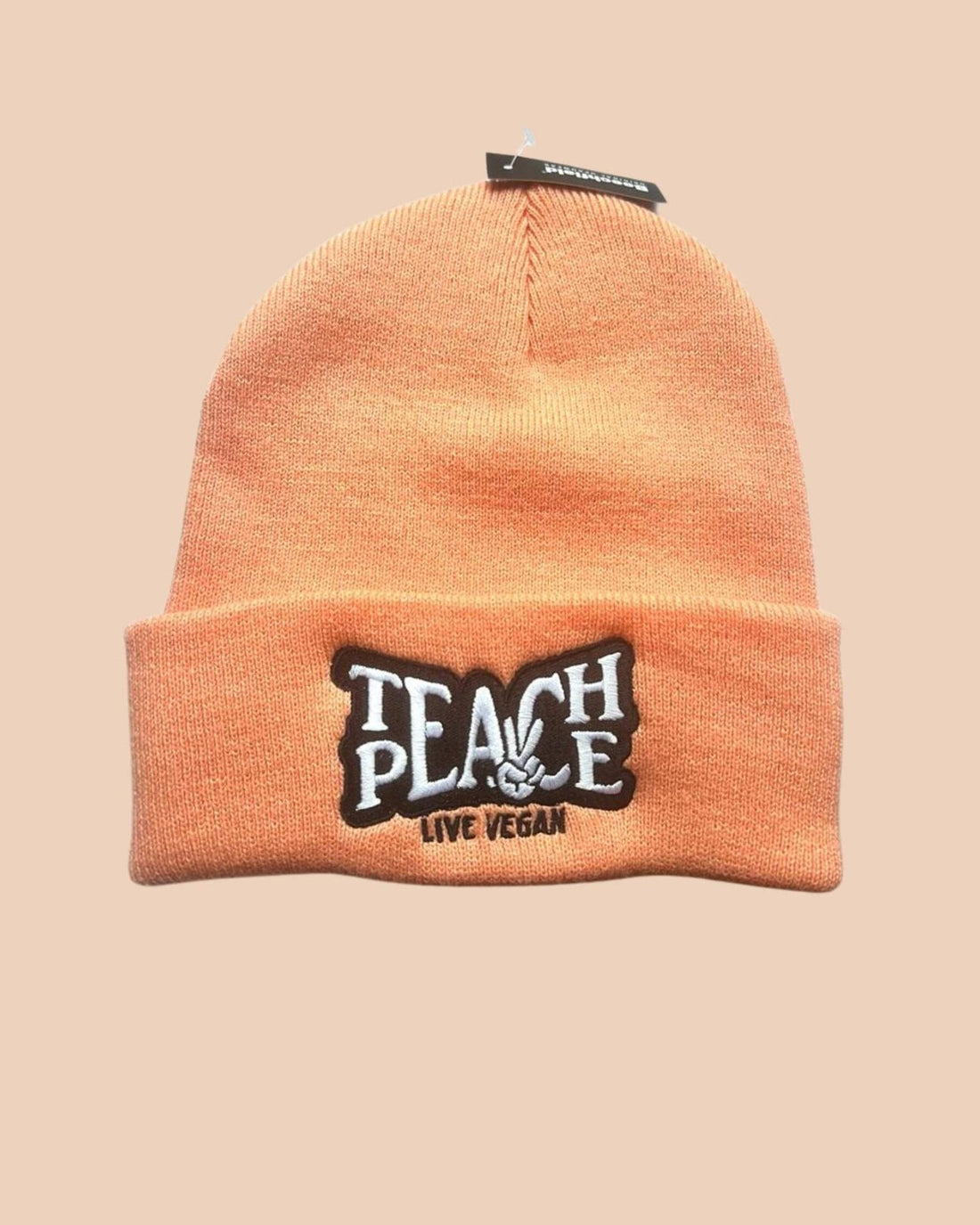 Flatlay photo of a cuffed beanie in Blush colour with a black and white embroidery &