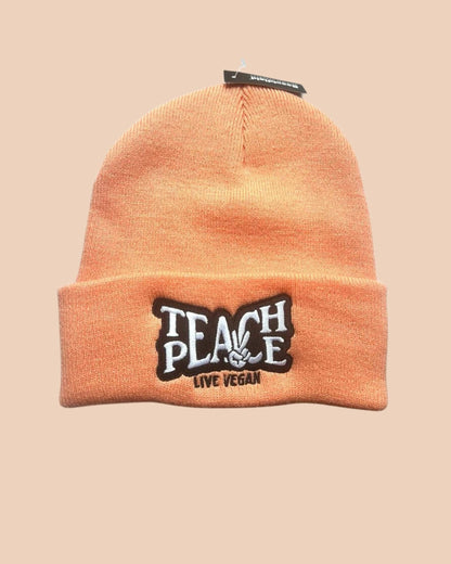 Flatlay photo of a cuffed beanie in Blush colour with a black and white embroidery &
