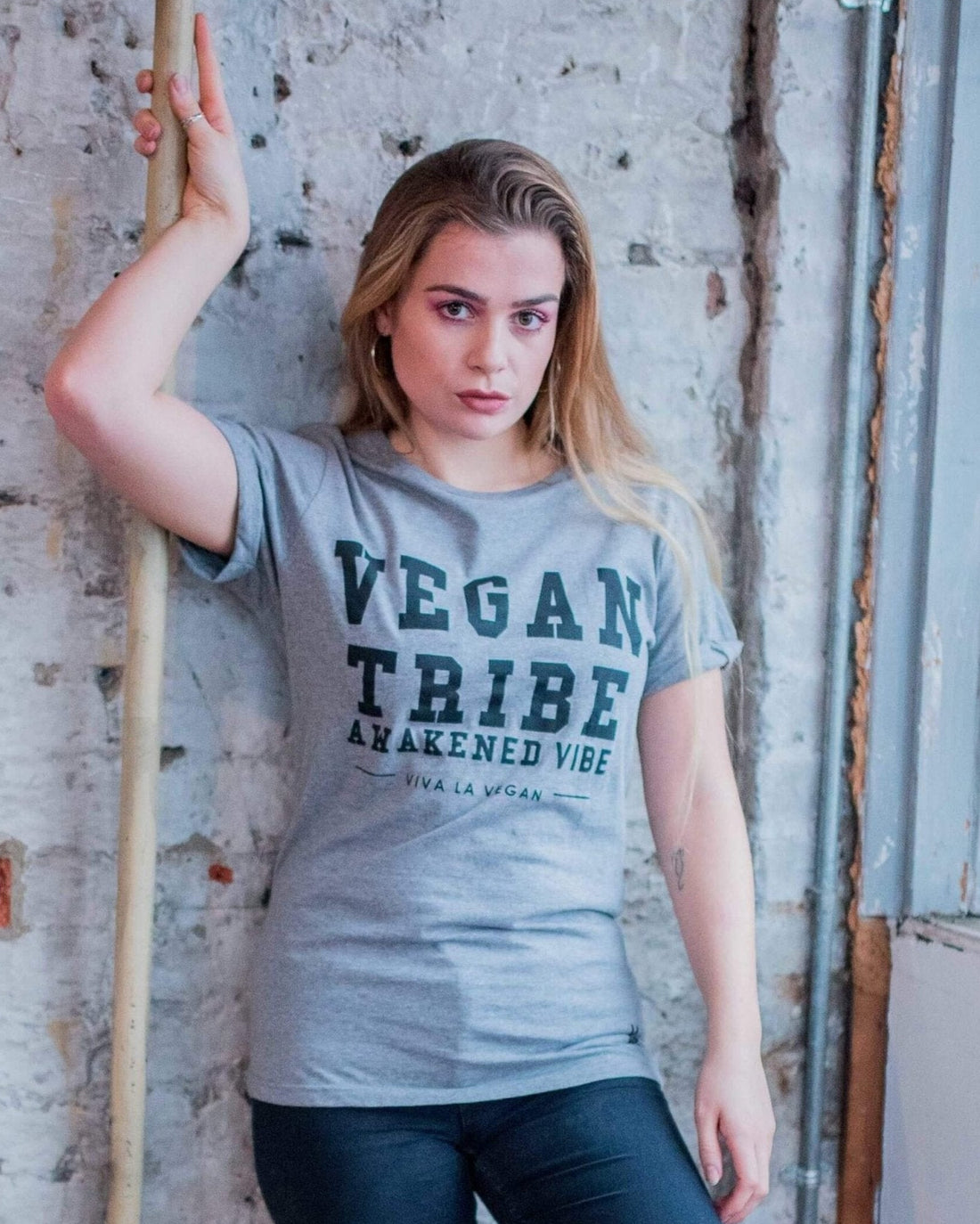A female model wearing Unisex grey marl tshirt. designed by eco-ethical brand Viva La Vegan with the words Vegan Tribe across the front