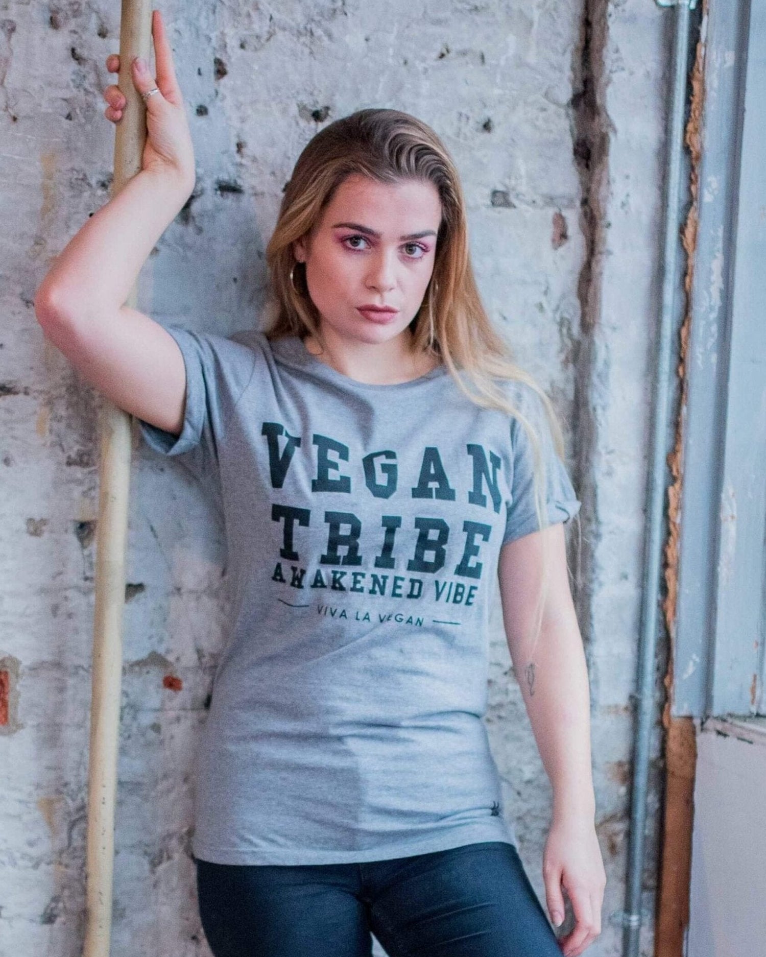 A female model wearing Unisex grey marl tshirt. designed by eco-ethical brand Viva La Vegan with the words Vegan Tribe across the front