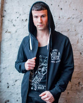 A male model standing against a white wall wearing a vegan activist hoodie phtograpghed from the front