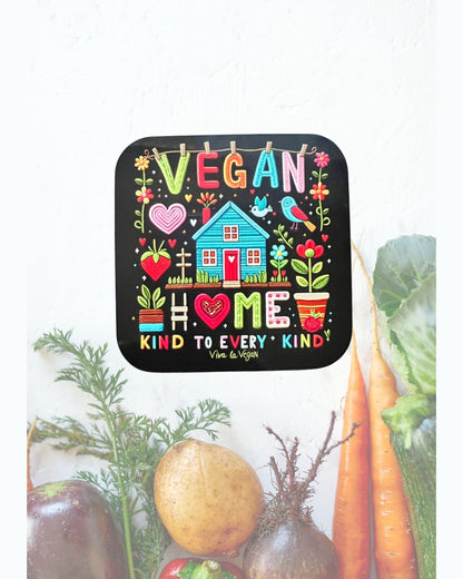 Vegan statement coaster with the wording Vegan Home a picture of a brightly coloured house in the style of embroidery. Black background with a colourful design