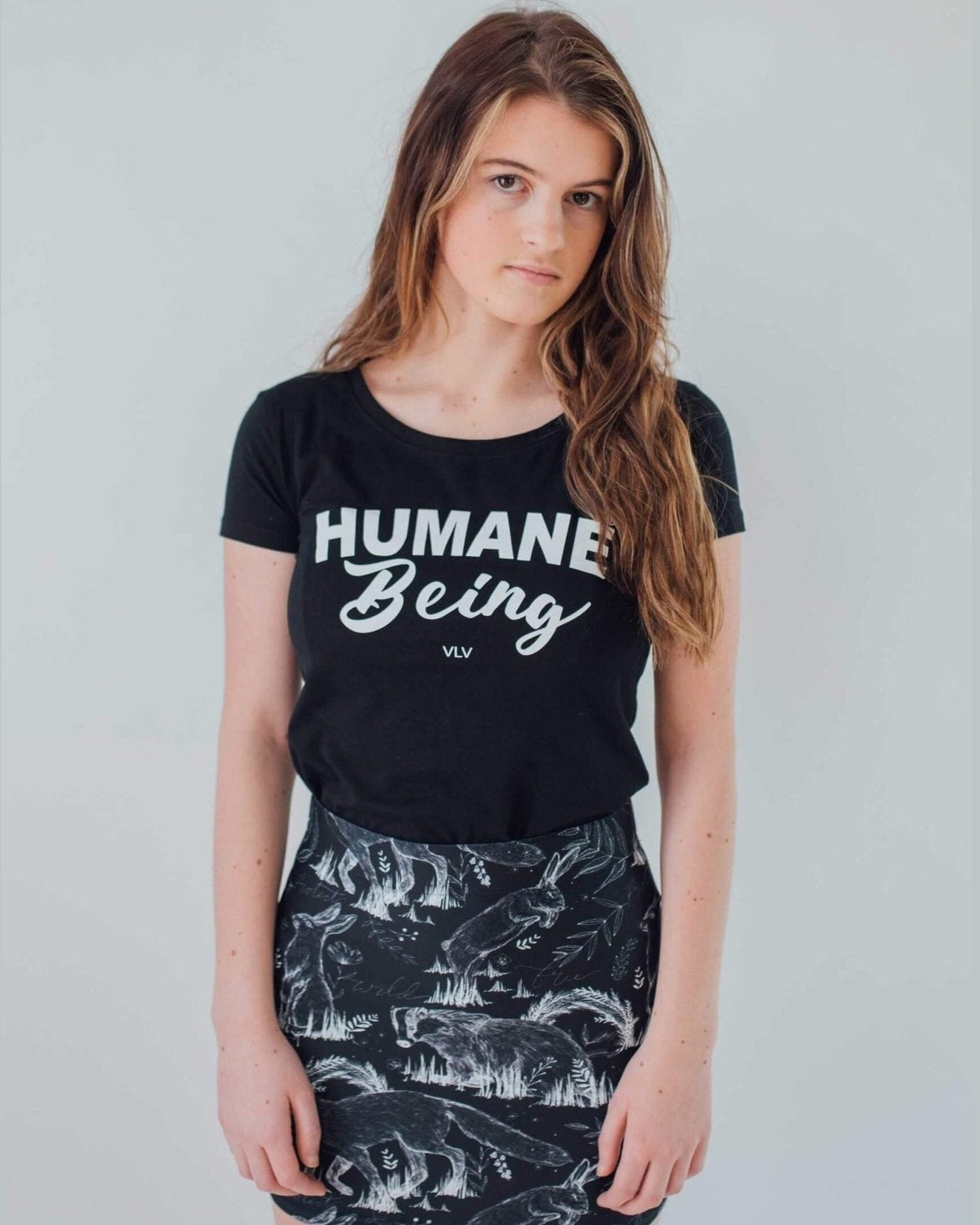 Female modelling the front of a black humane being vegan tshirt on a white background on behalf the Eco ethical vegan brand Viva La Vegan.