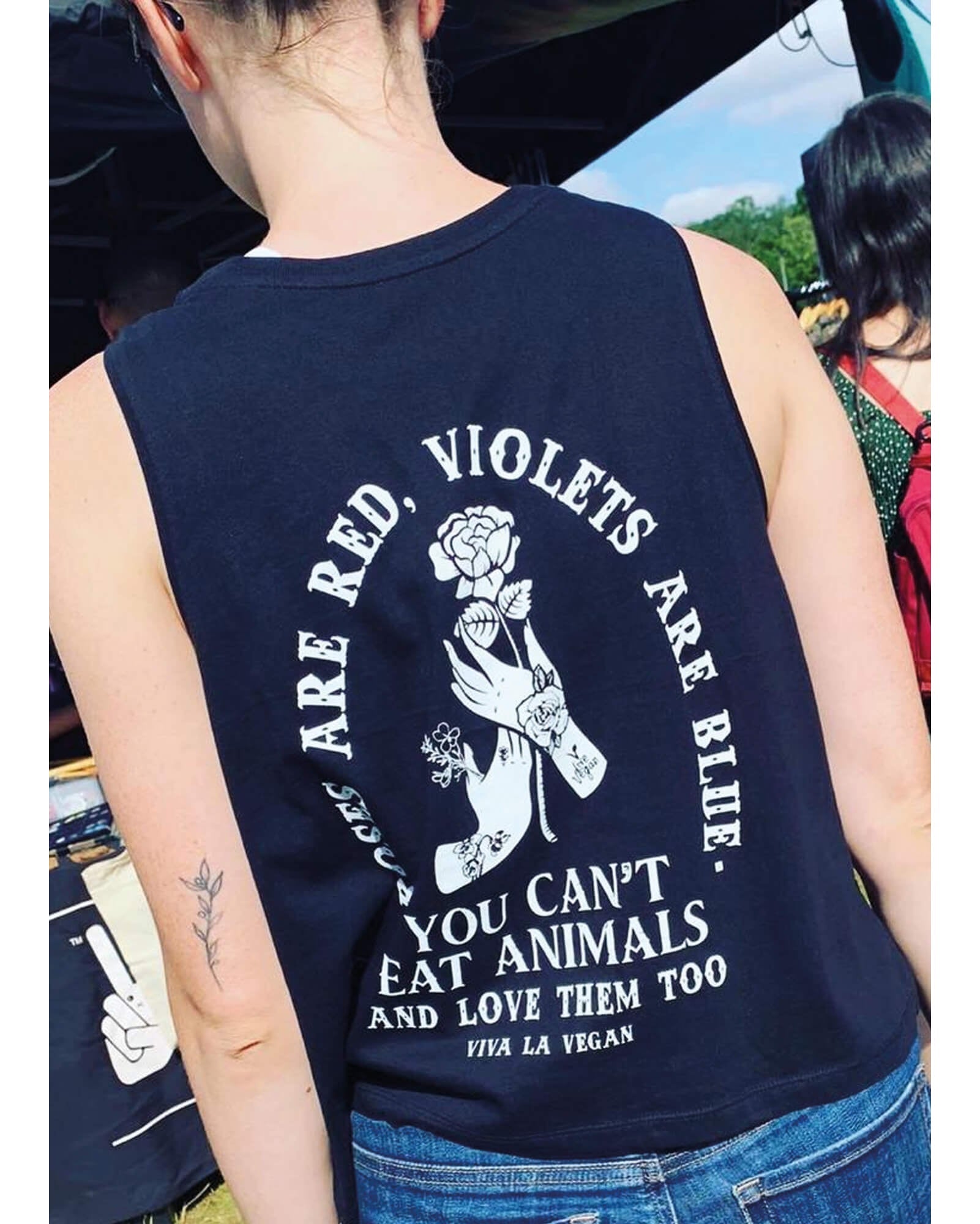 Back of festival girl wearing a black vest with the graphic, Roses are red violets are blue you can&